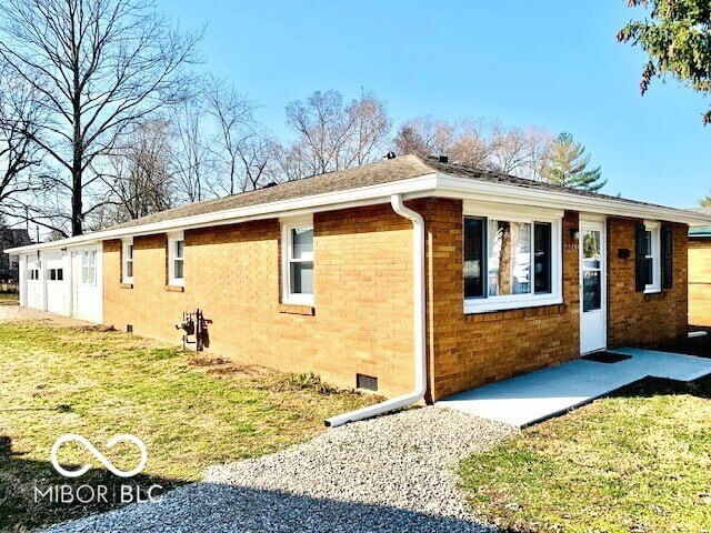 view of side of property with crawl space, a garage, a yard, and brick siding