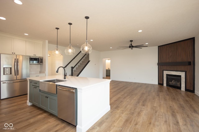 kitchen with stainless steel appliances, a kitchen island with sink, ceiling fan, pendant lighting, and white cabinetry