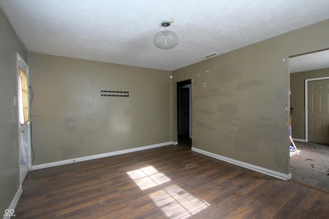 unfurnished room with a textured ceiling and dark hardwood / wood-style flooring