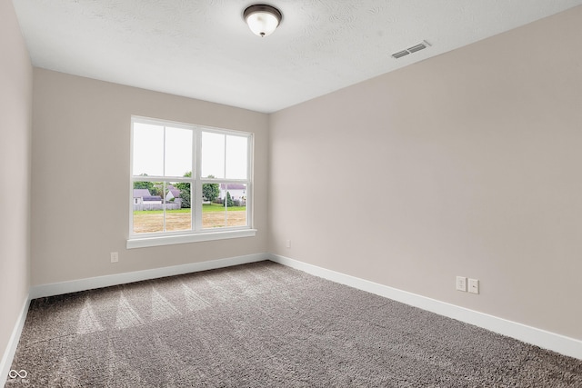 carpeted empty room featuring a textured ceiling