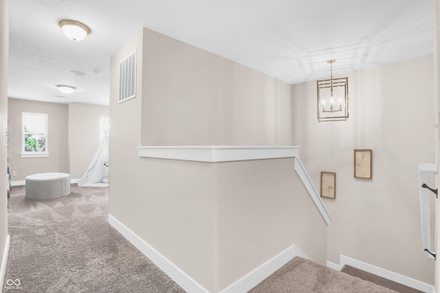 stairway with carpet floors and a chandelier