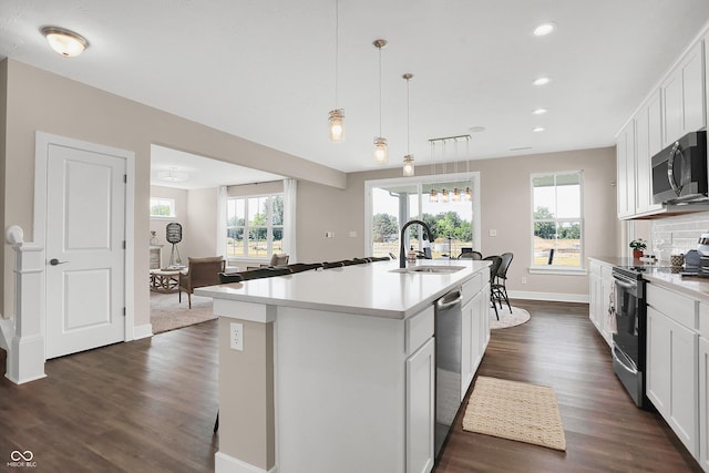 kitchen with appliances with stainless steel finishes, dark wood-type flooring, sink, a center island with sink, and white cabinetry