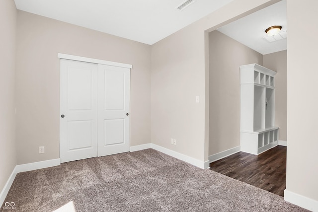 unfurnished bedroom with dark colored carpet and a closet