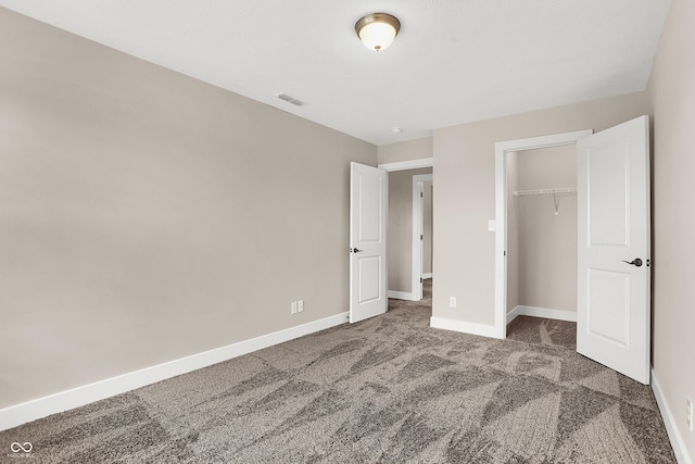 unfurnished bedroom with dark colored carpet and a closet