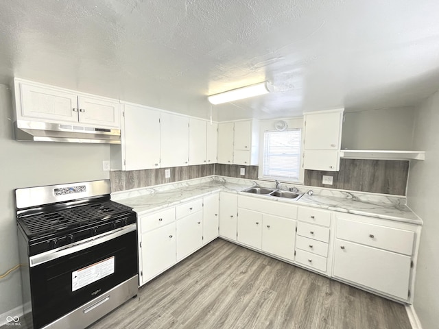 kitchen featuring white cabinets, sink, light hardwood / wood-style flooring, a textured ceiling, and stainless steel range oven