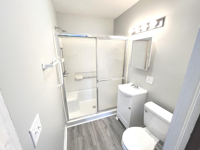 bathroom with vanity, a shower with door, hardwood / wood-style flooring, toilet, and a textured ceiling