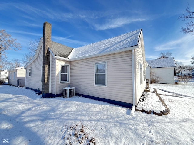 snow covered rear of property featuring central air condition unit