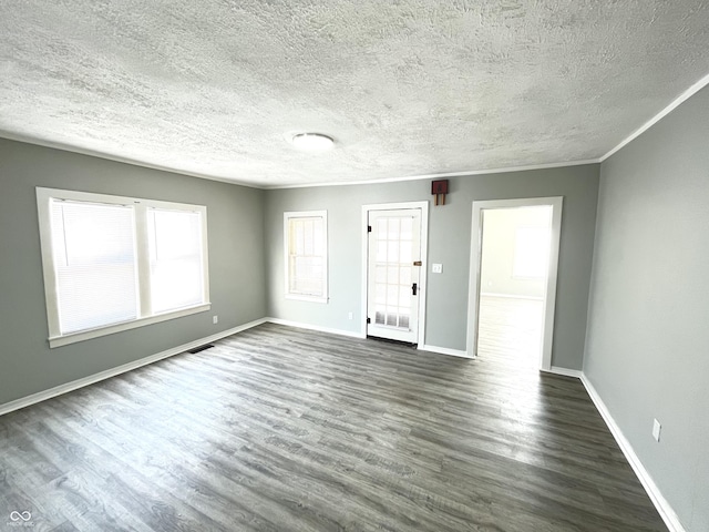 empty room featuring a textured ceiling, crown molding, and dark hardwood / wood-style floors