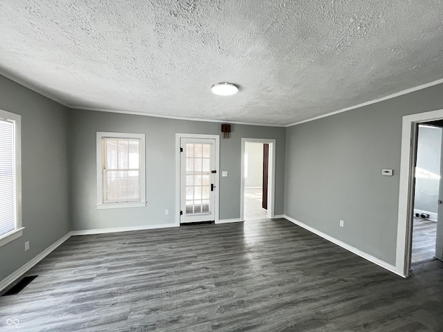 empty room featuring dark hardwood / wood-style flooring, ornamental molding, and a textured ceiling