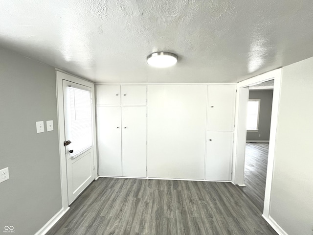 interior space featuring a textured ceiling, dark wood-type flooring, and a closet