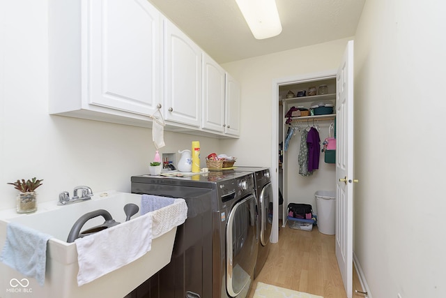 laundry area featuring washer and dryer, light hardwood / wood-style floors, and cabinets