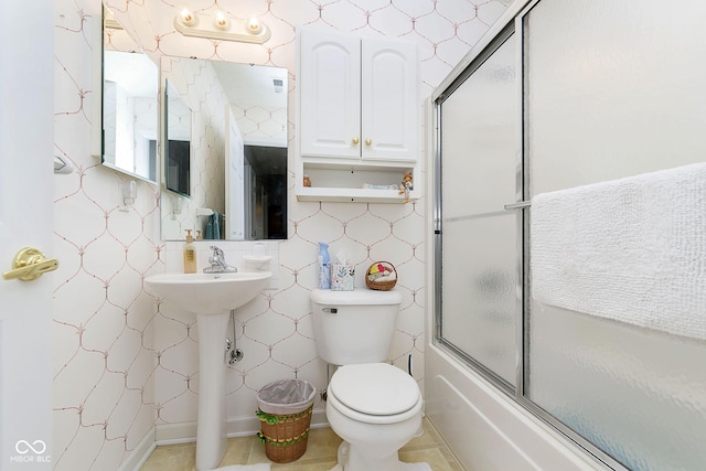 full bathroom with combined bath / shower with glass door, tile patterned flooring, toilet, and sink