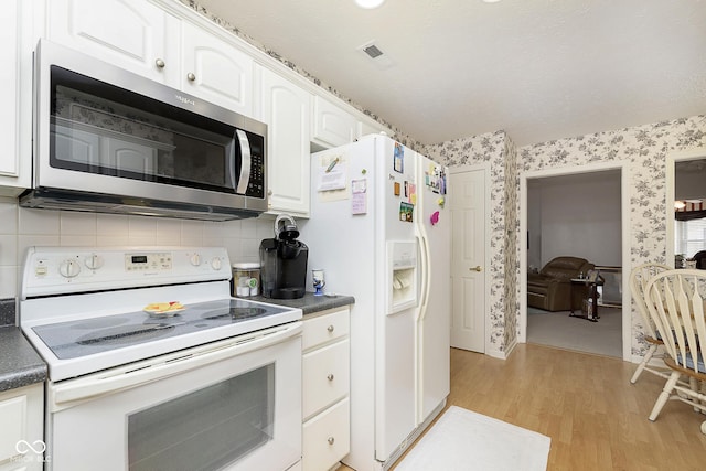 kitchen featuring white cabinets, light wood-type flooring, white appliances, and tasteful backsplash