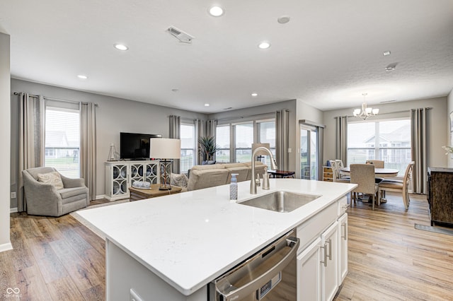 kitchen featuring white cabinets, a center island with sink, sink, light hardwood / wood-style flooring, and stainless steel dishwasher