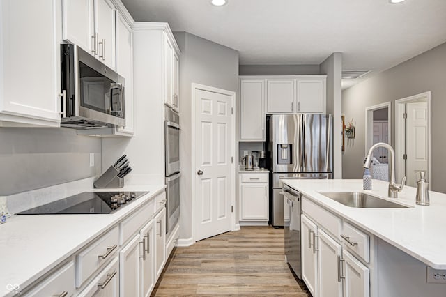 kitchen featuring sink, white cabinetry, stainless steel appliances, and light hardwood / wood-style flooring