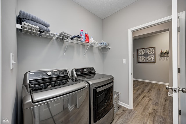 laundry area featuring washer and clothes dryer, wood-type flooring, and a textured ceiling