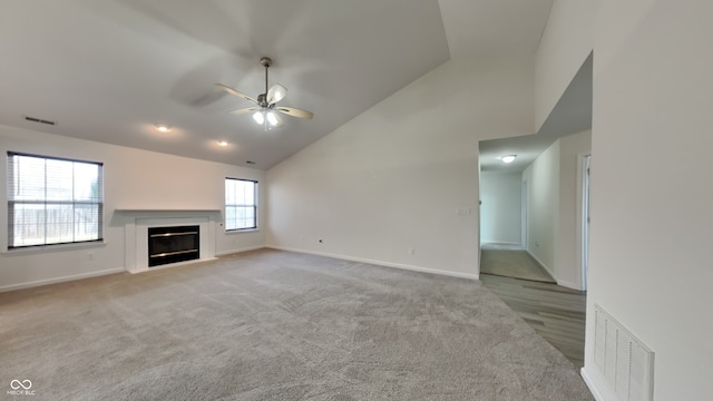 unfurnished living room with ceiling fan, high vaulted ceiling, and light colored carpet