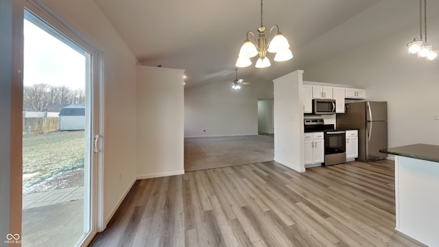 kitchen with dark countertops, appliances with stainless steel finishes, white cabinets, light wood finished floors, and lofted ceiling