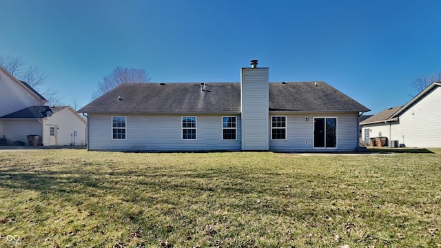 back of house with a yard, roof with shingles, and a chimney