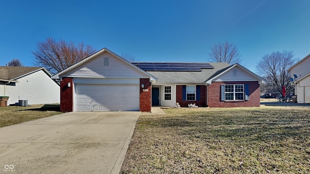 single story home featuring brick siding, concrete driveway, a front yard, roof mounted solar panels, and a garage