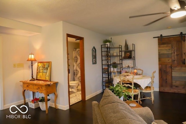 interior space with dark hardwood / wood-style flooring, a barn door, and ceiling fan