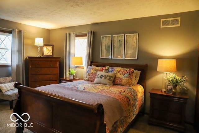 bedroom featuring a textured ceiling and dark colored carpet