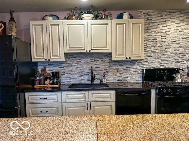 kitchen featuring light stone countertops, sink, tasteful backsplash, and black appliances