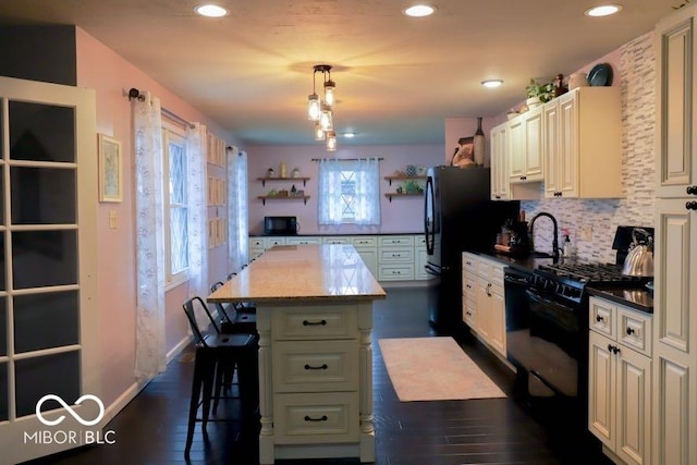 kitchen with a center island, dark wood-type flooring, black appliances, decorative light fixtures, and a breakfast bar area