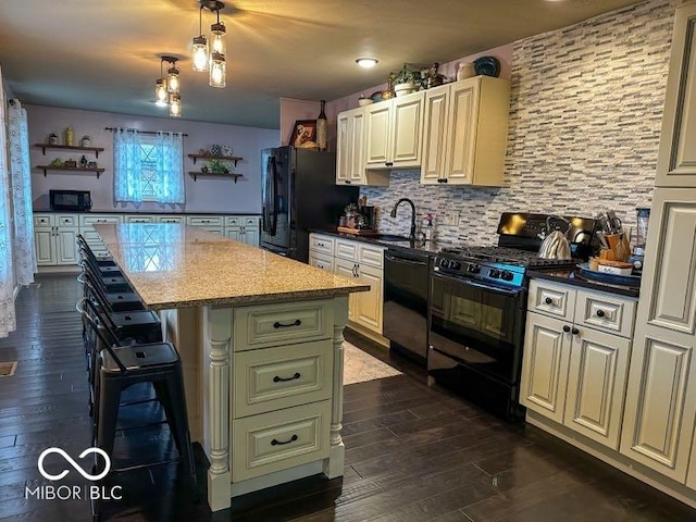 kitchen with pendant lighting, a center island, dark wood-type flooring, black appliances, and a breakfast bar area