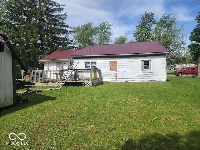 rear view of house featuring a wooden deck and a yard