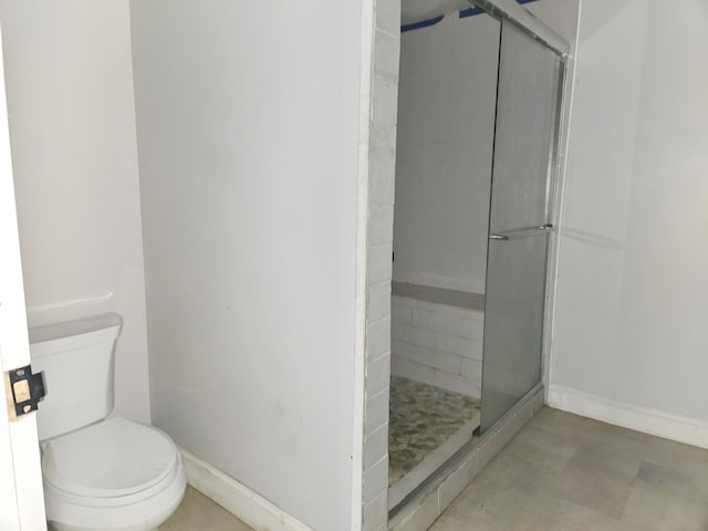 bathroom with a shower with door and toilet