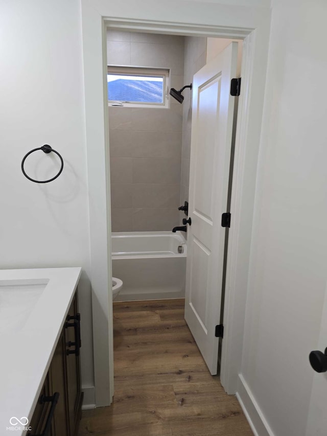 full bathroom with hardwood / wood-style flooring, vanity, toilet, and tiled shower / bath