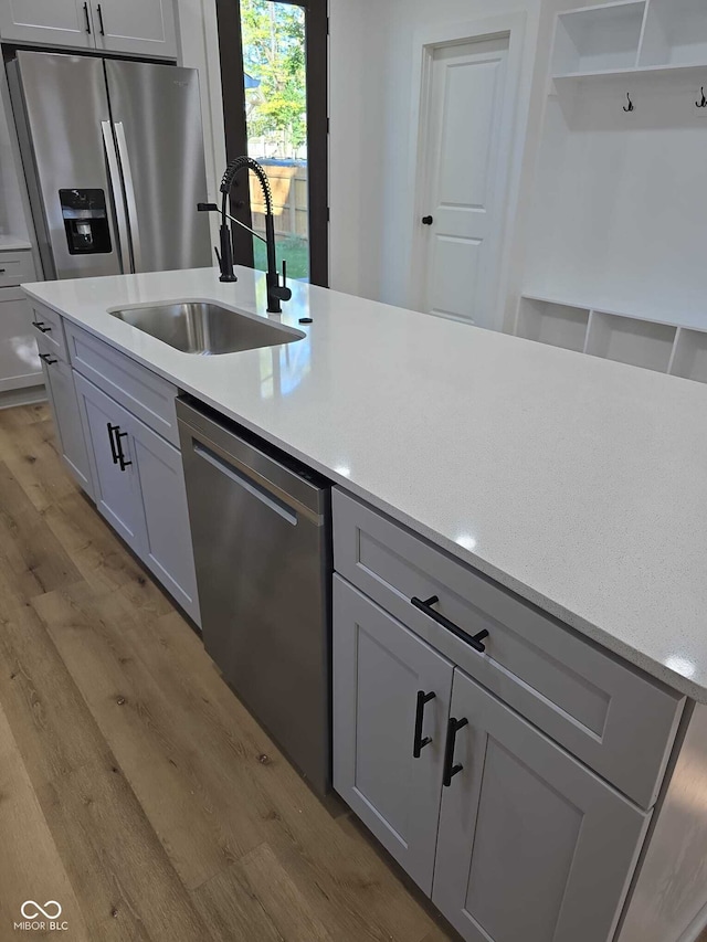 kitchen featuring appliances with stainless steel finishes, light wood-type flooring, gray cabinetry, and sink