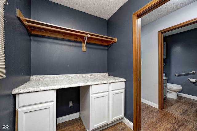 laundry room featuring a textured ceiling, dark wood finished floors, and baseboards