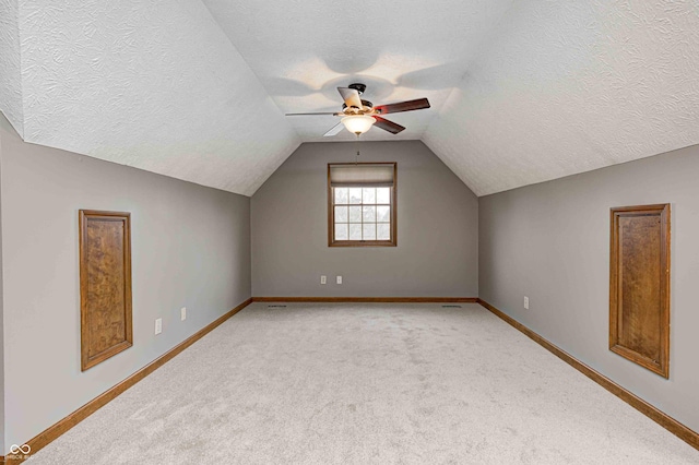 bonus room with lofted ceiling, light carpet, and a textured ceiling