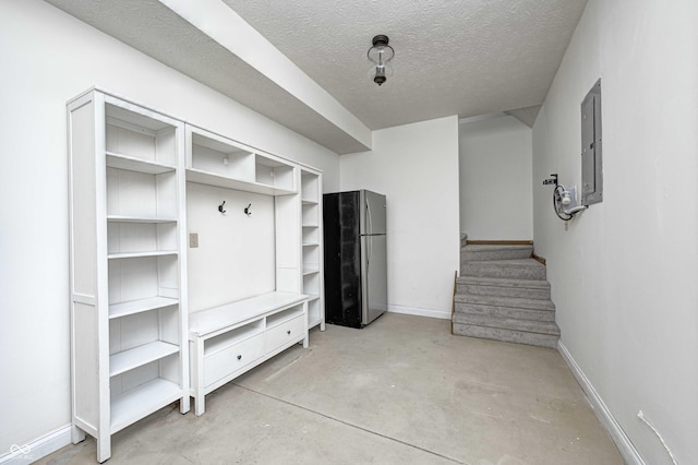 mudroom with electric panel and a textured ceiling