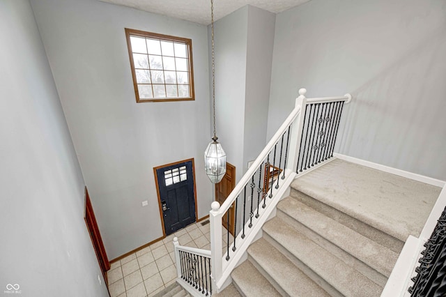 staircase with carpet flooring, a textured ceiling, and a notable chandelier