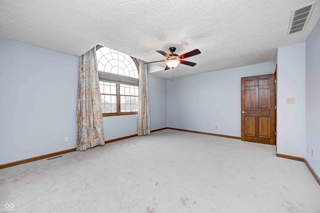 empty room with ceiling fan, light colored carpet, and a textured ceiling