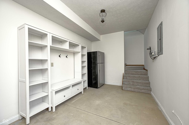 mudroom with concrete flooring, electric panel, a textured ceiling, and baseboards