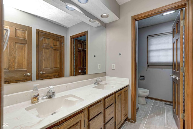 bathroom featuring vanity, toilet, and a textured ceiling