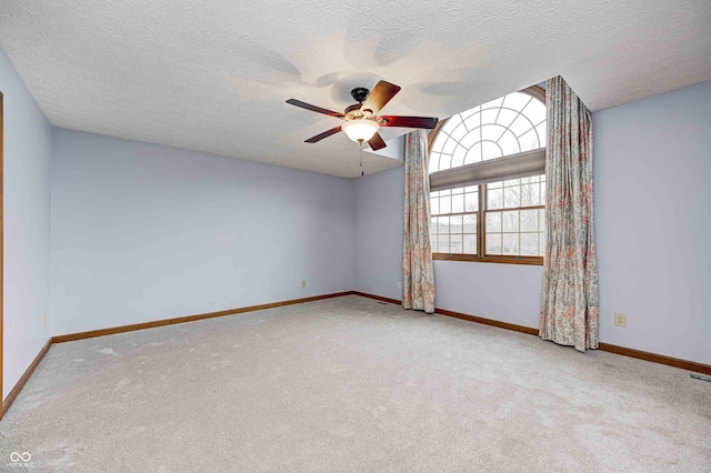 empty room featuring baseboards, ceiling fan, and light colored carpet