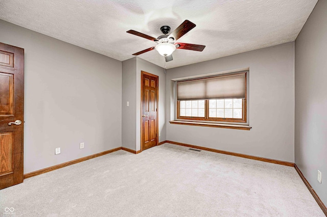 unfurnished bedroom featuring ceiling fan, a textured ceiling, and light carpet