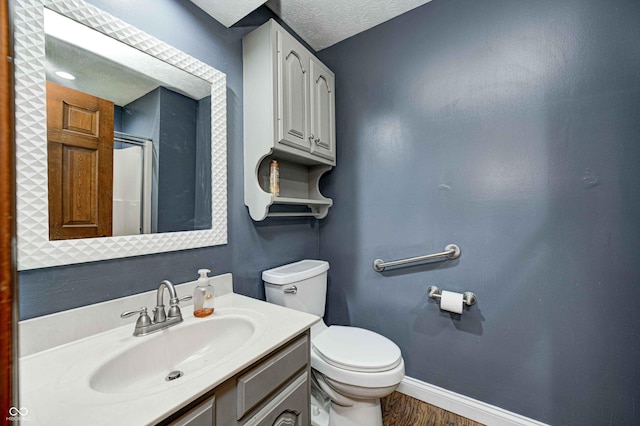 bathroom featuring baseboards, toilet, wood finished floors, a textured ceiling, and vanity