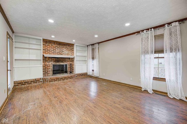 unfurnished living room featuring built in features, a fireplace, a textured ceiling, and wood finished floors