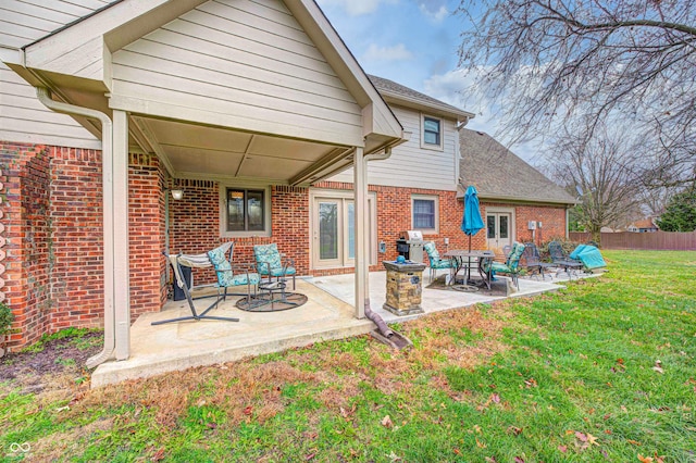 rear view of property with a patio area, a yard, brick siding, and fence