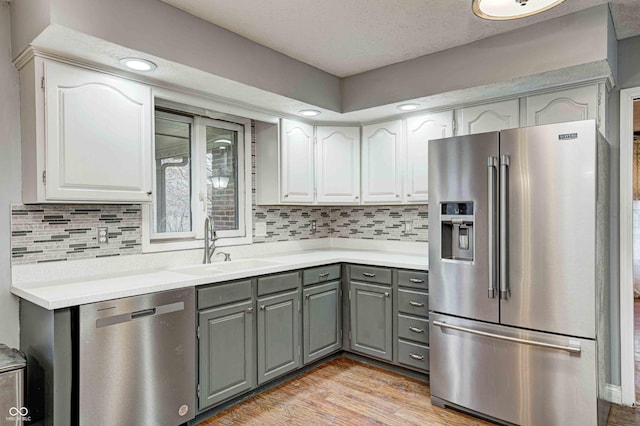 kitchen featuring a sink, light countertops, appliances with stainless steel finishes, light wood-type flooring, and gray cabinets