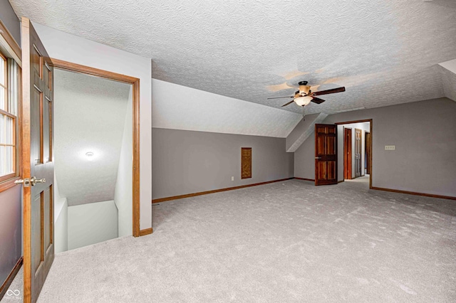 additional living space with carpet, ceiling fan, lofted ceiling, and a textured ceiling