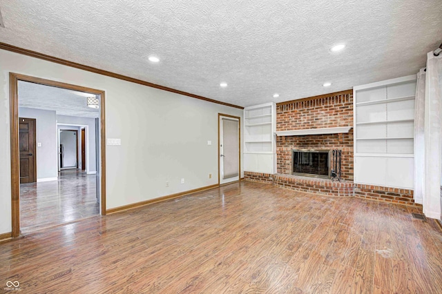 unfurnished living room featuring a brick fireplace, crown molding, a textured ceiling, and hardwood / wood-style flooring