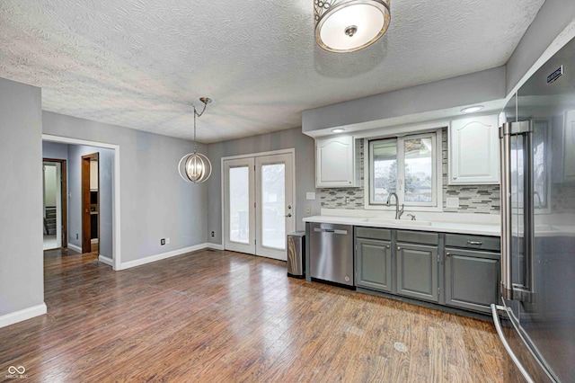 kitchen featuring stainless steel appliances, light countertops, gray cabinetry, dark wood-type flooring, and a sink