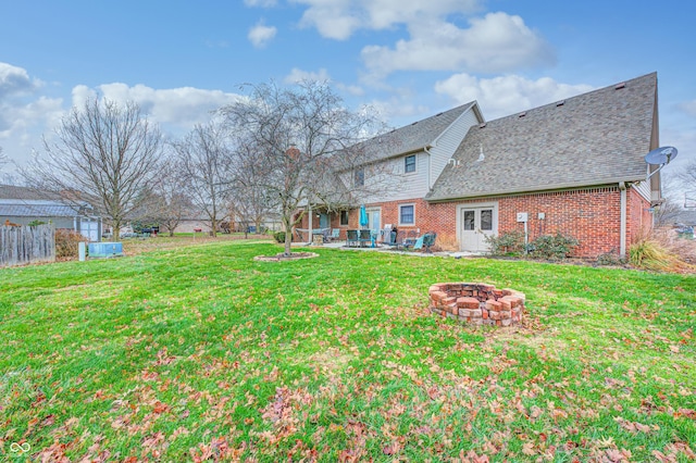 rear view of house with a patio area, brick siding, a yard, and a fire pit